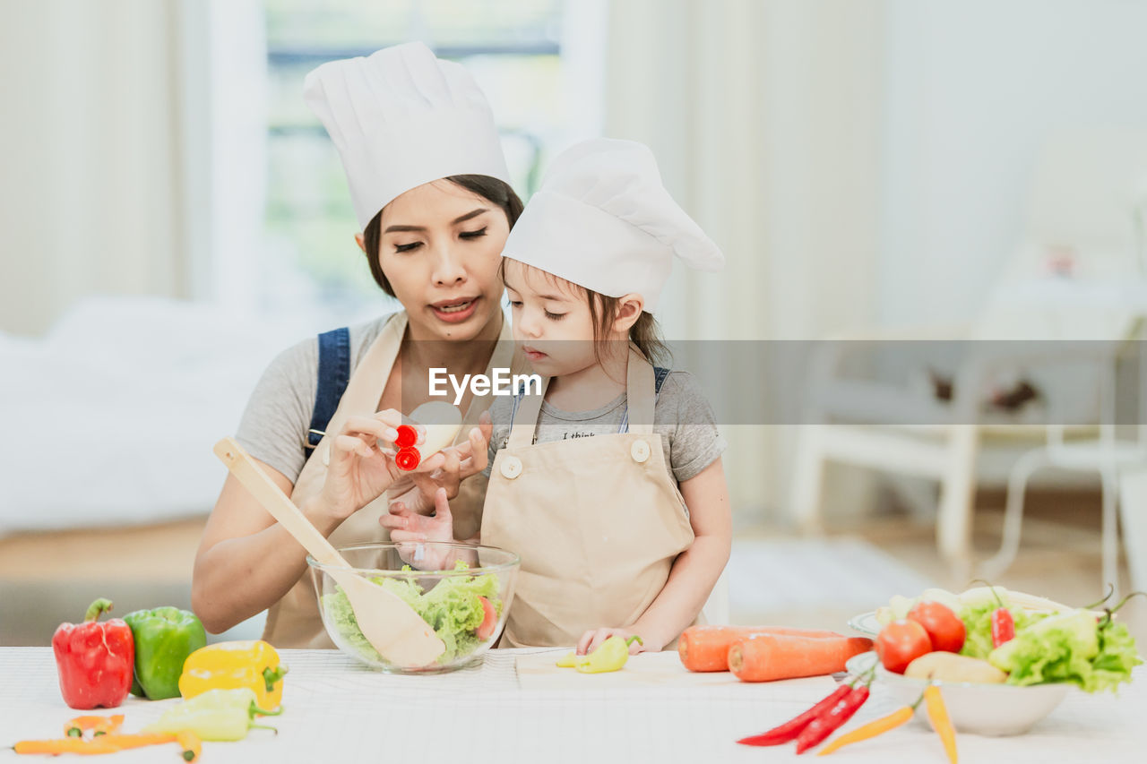 Mother and daughter preparing food on table