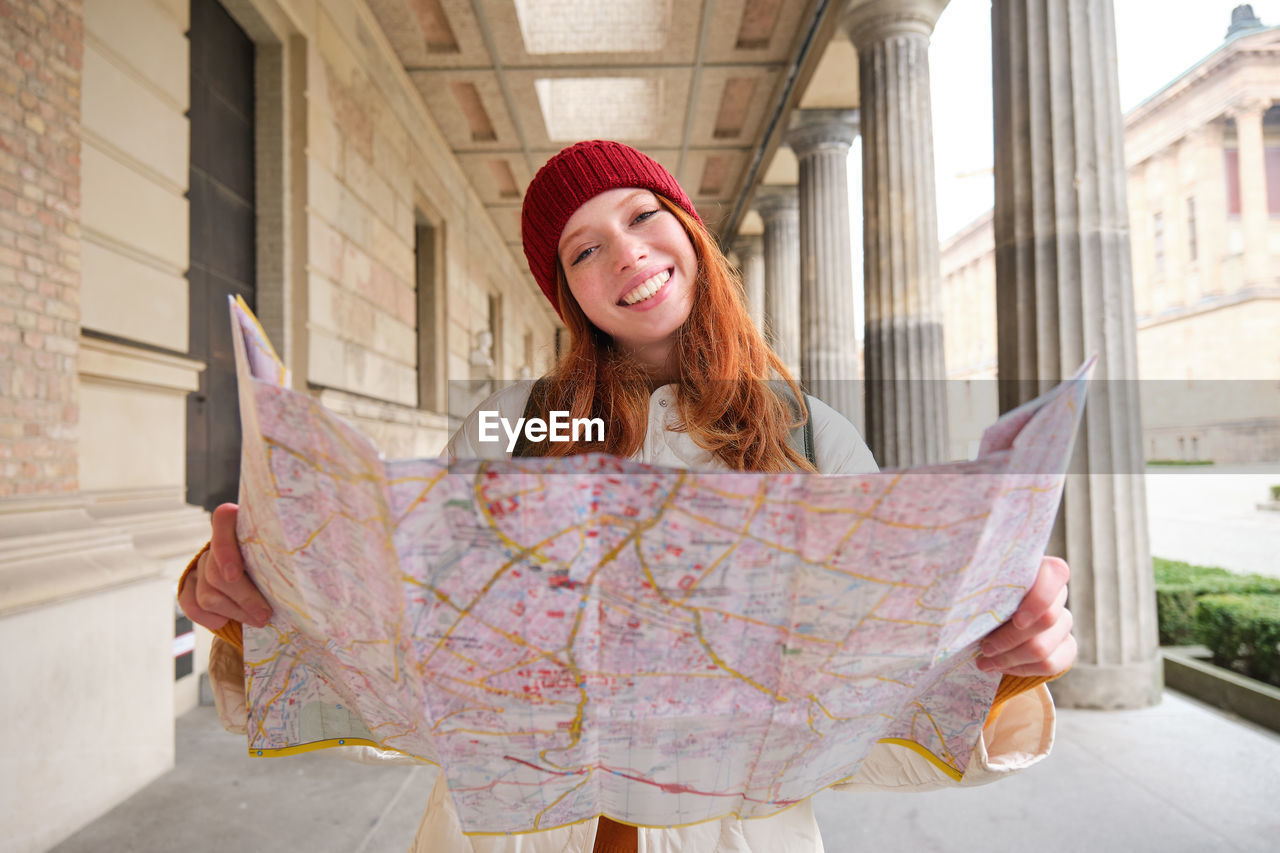 portrait of smiling young woman standing against building