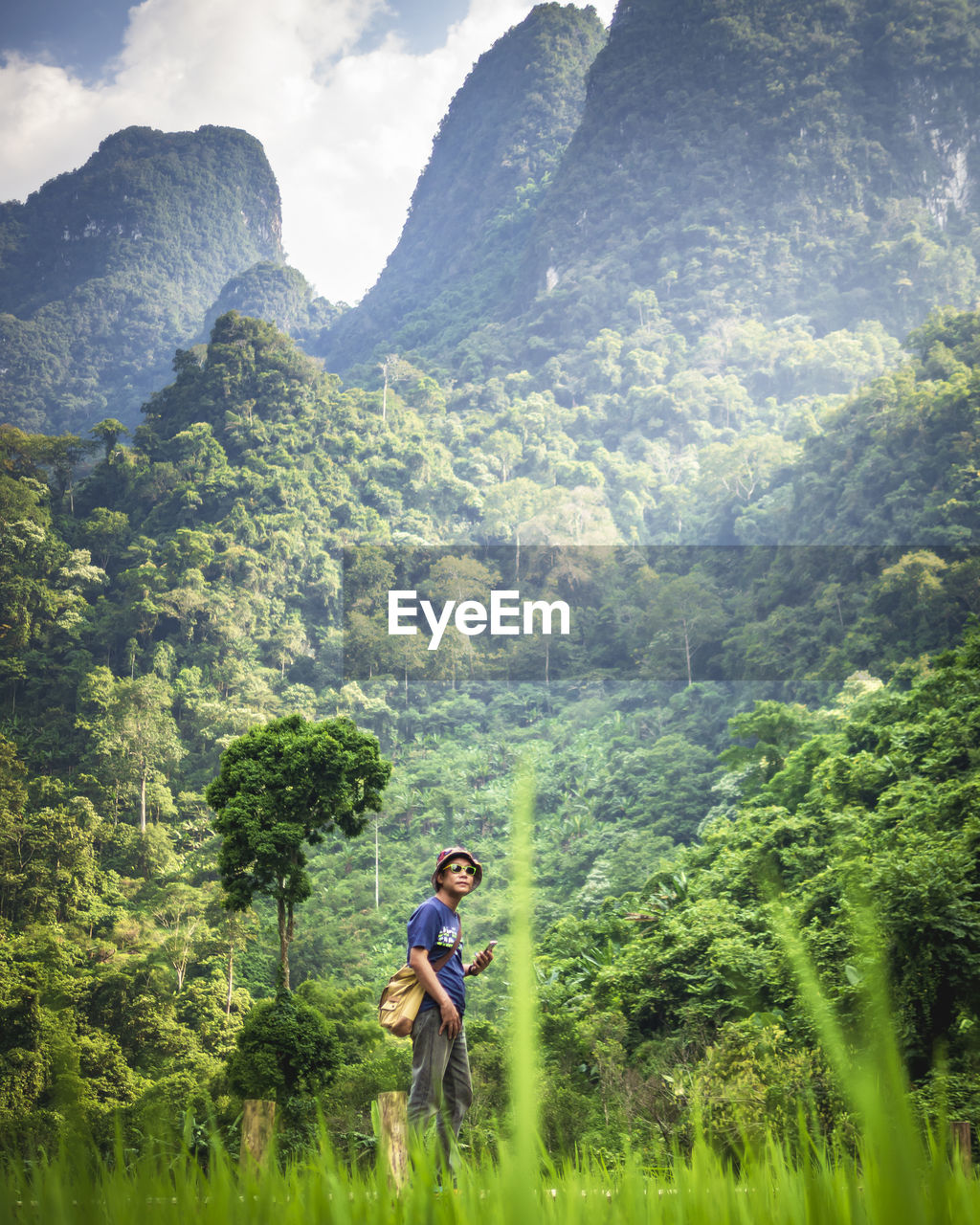 Man standing on land against tree mountains