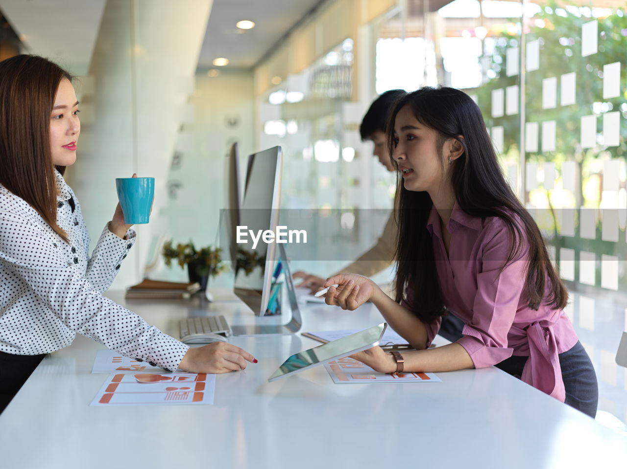 Coworkers discussing at desk in office