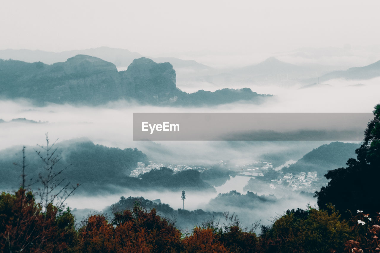 SCENIC VIEW OF MOUNTAINS IN FOGGY WEATHER AGAINST SKY