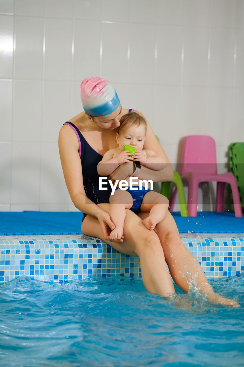 Early age swimming in pool. baby boy waiting near side, learning shapes and fruits. happy child 