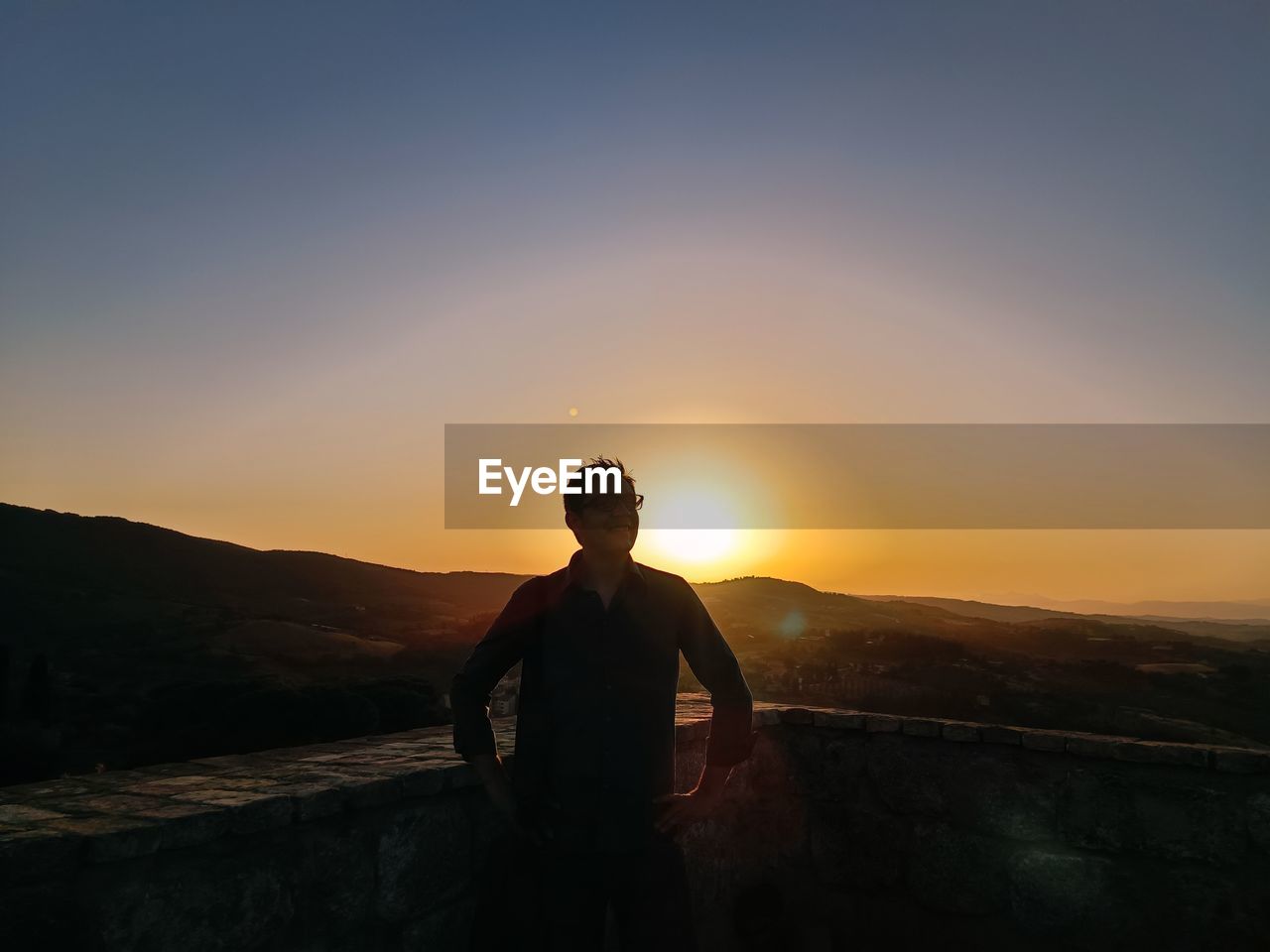 Portrait of young man standing against sky during sunset