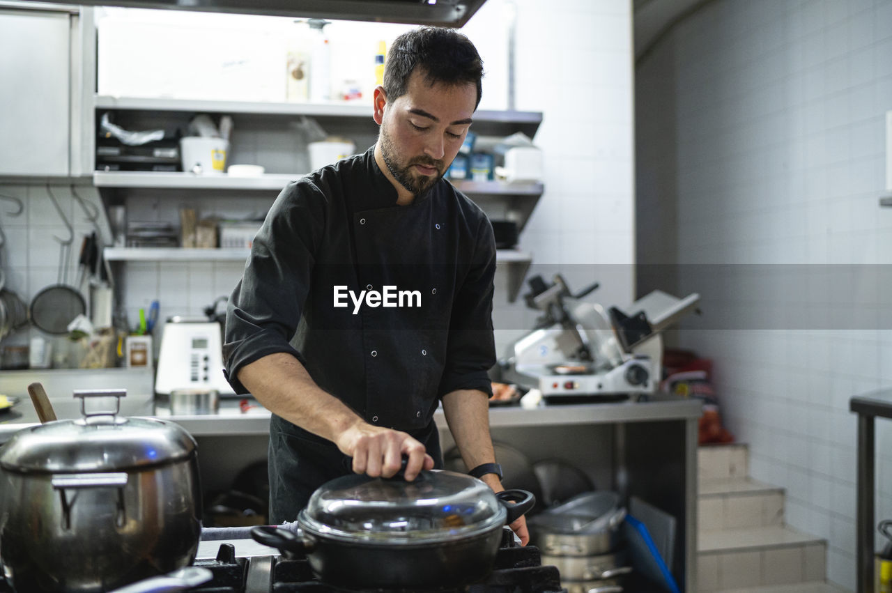 Man working while standing at commercial kitchen