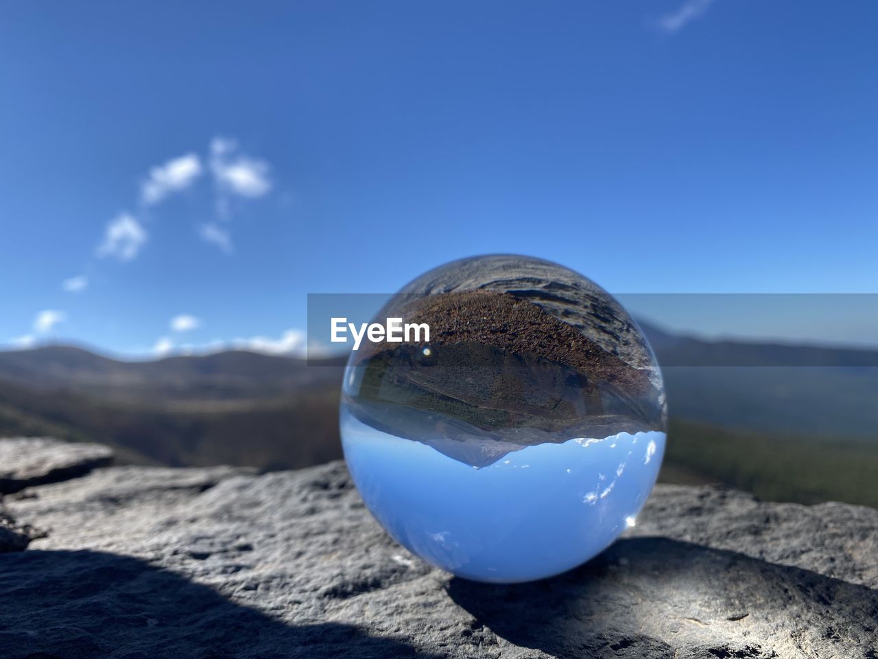 blue, sky, reflection, nature, sphere, environment, landscape, cloud, scenics - nature, no people, land, sea, sunlight, mountain, outdoors, day, physical geography, water, beauty in nature, globe - man made object, travel, shadow, rock, travel destinations, earth, planet earth, shape, crystal ball, single object, space, sunny, tranquility, tranquil scene, focus on foreground