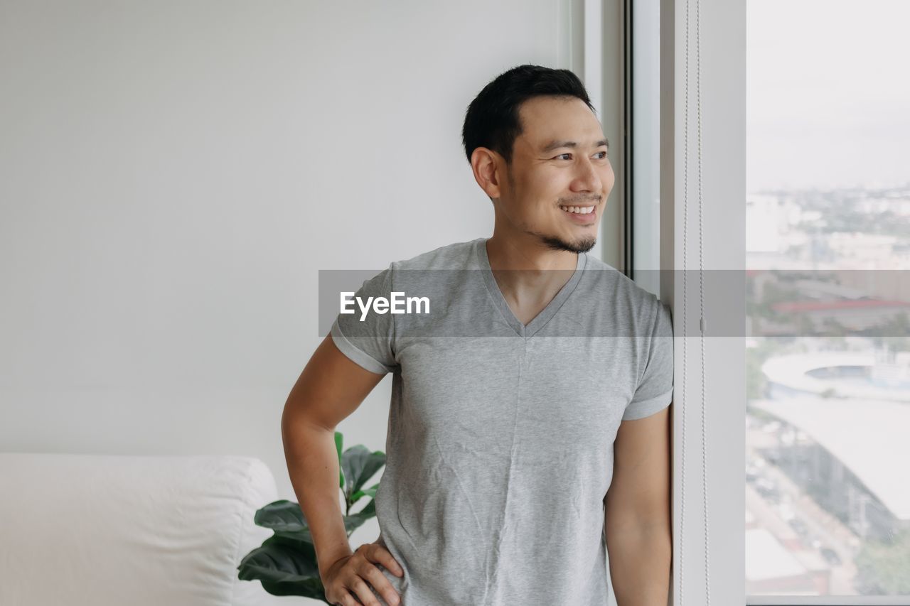 portrait of young man standing by window