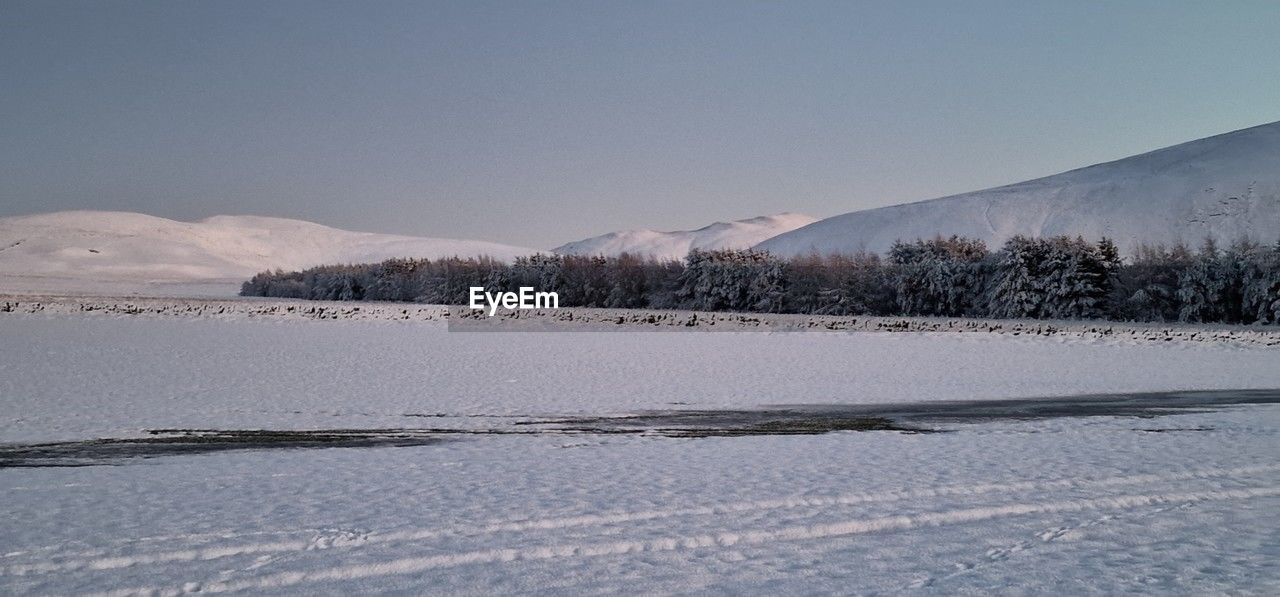 winter, snow, cold temperature, mountain, environment, landscape, scenics - nature, nature, sky, beauty in nature, tree, land, freezing, tranquil scene, no people, plant, tranquility, water, frozen, ice, non-urban scene, travel destinations, lake, travel, frost, coniferous tree, mountain range, day, pinaceae, outdoors, blue, snowcapped mountain, tourism, pine tree, forest, pine woodland, piste, clear sky, polar climate