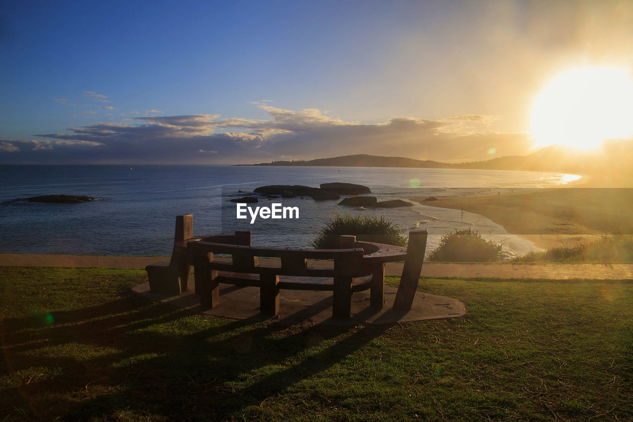 sky, water, morning, sea, nature, sunlight, land, beauty in nature, horizon, scenics - nature, sun, sunrise, tranquility, beach, dusk, environment, landscape, tranquil scene, coast, cloud, grass, ocean, travel destinations, seat, idyllic, summer, no people, travel, shore, plant, sunbeam, outdoors, vacation, trip, relaxation, holiday, coastline, bench, reflection, lens flare, horizon over water, seascape, tourism, wood, twilight, non-urban scene, architecture, chair, body of water, blue