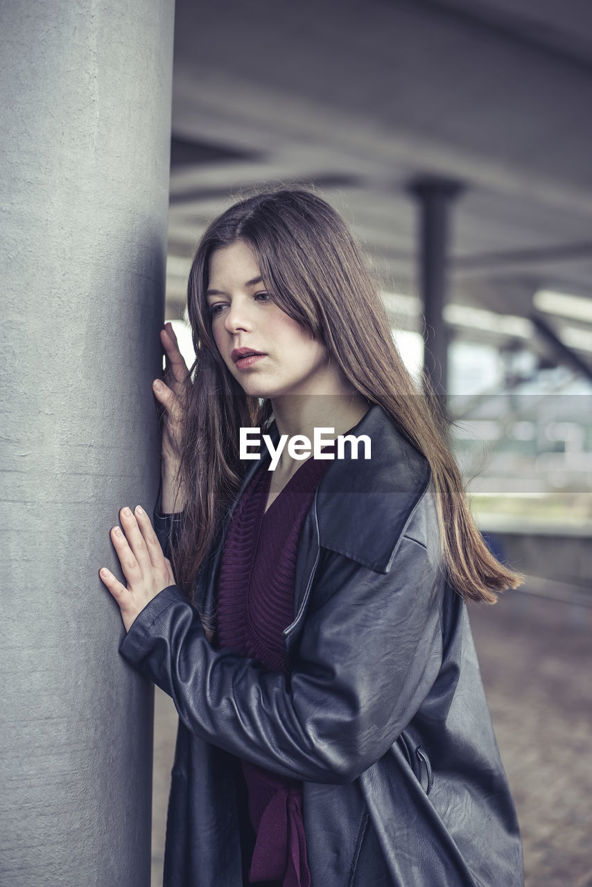 portrait of smiling young woman standing against building