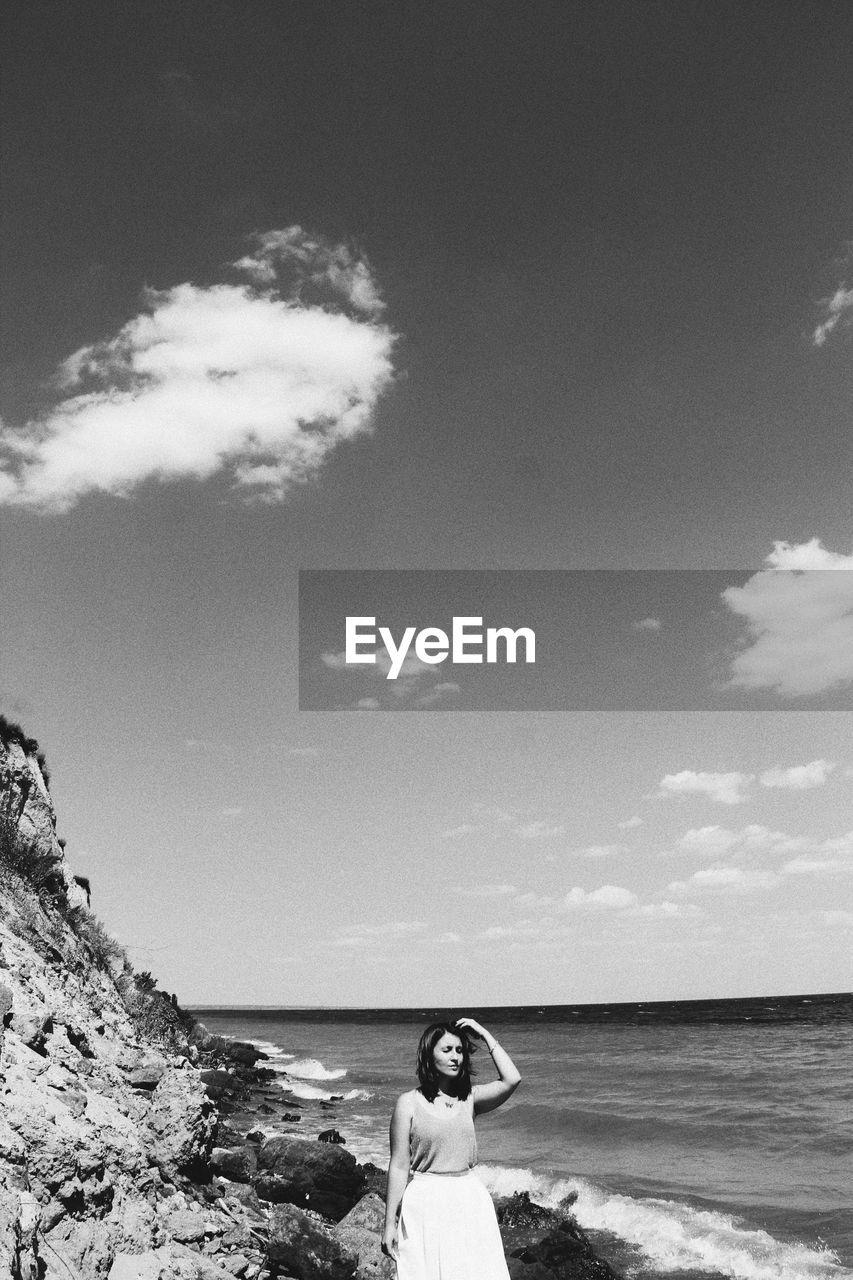 Woman standing on beach against sky