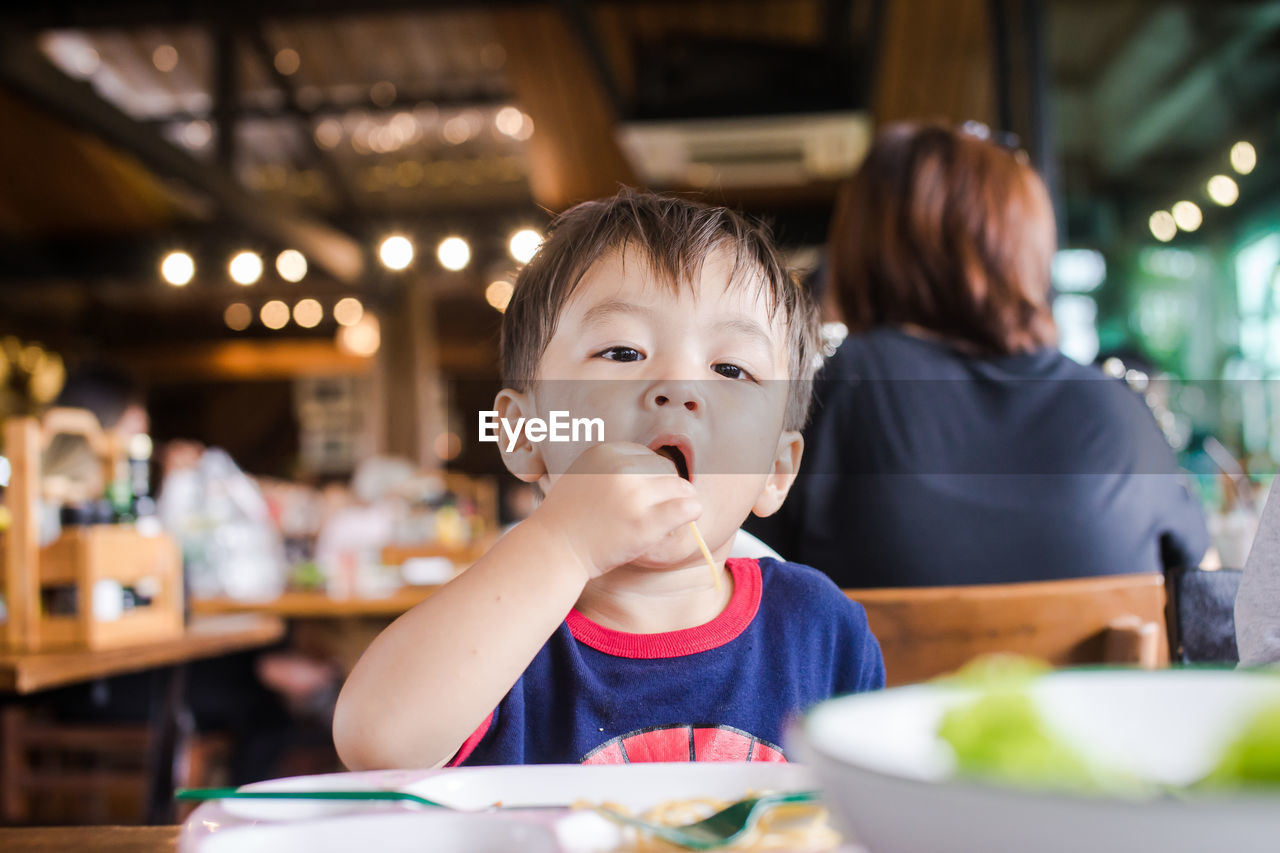 Cute baby boy having meal at restaurant