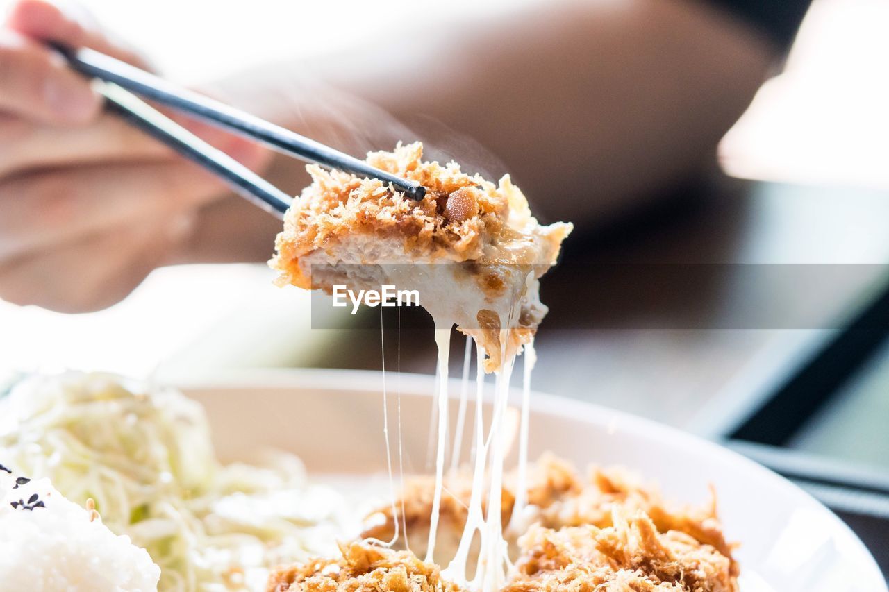 Close-up of hand holding chicken in chopsticks