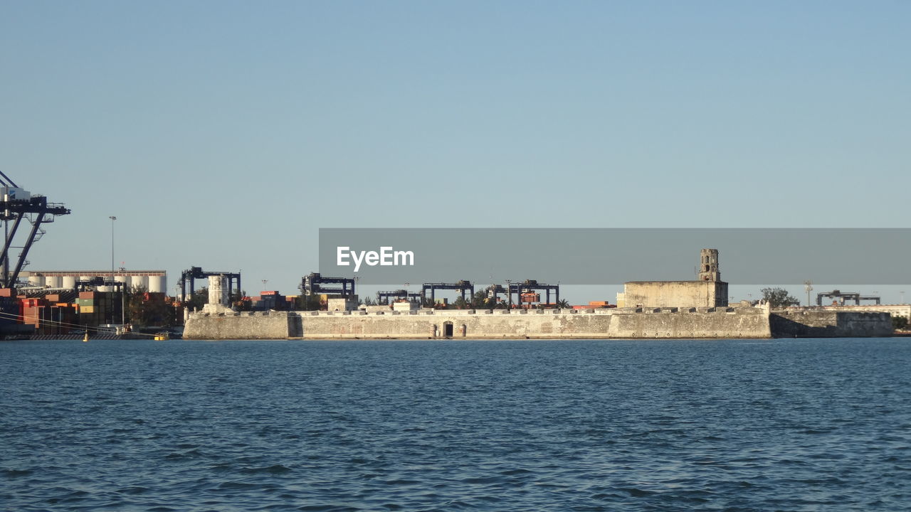 Sea and cityscape against clear sky