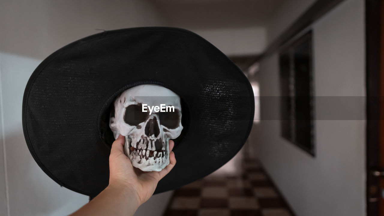 Cropped hand holding skull with hat