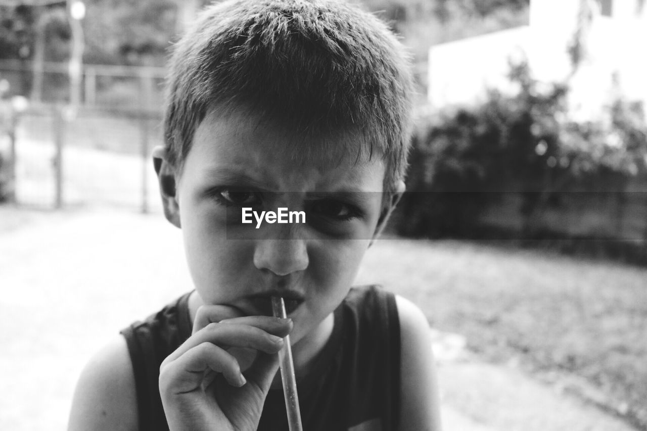 Close-up portrait of boy with drinking straw in mouth