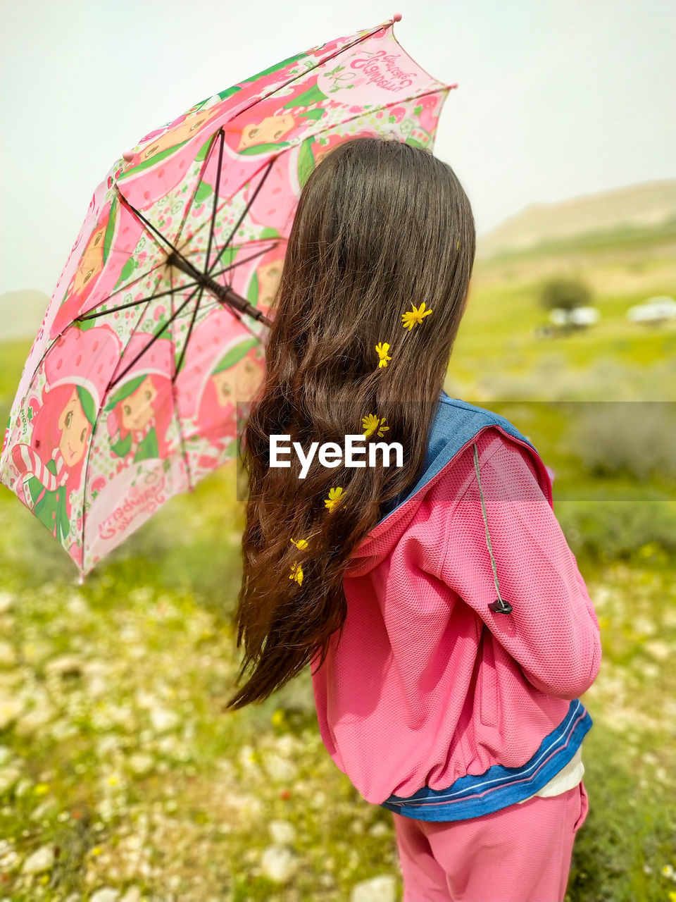 Rear view of woman standing with a pink umbrella