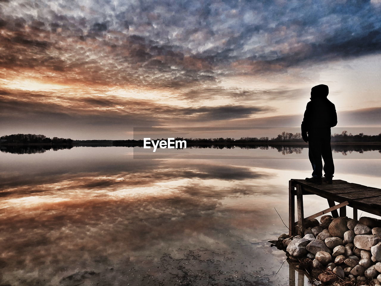 MAN STANDING ON LAKE AGAINST SKY