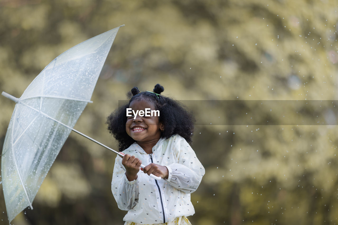 portrait of smiling young woman with umbrella standing against sky