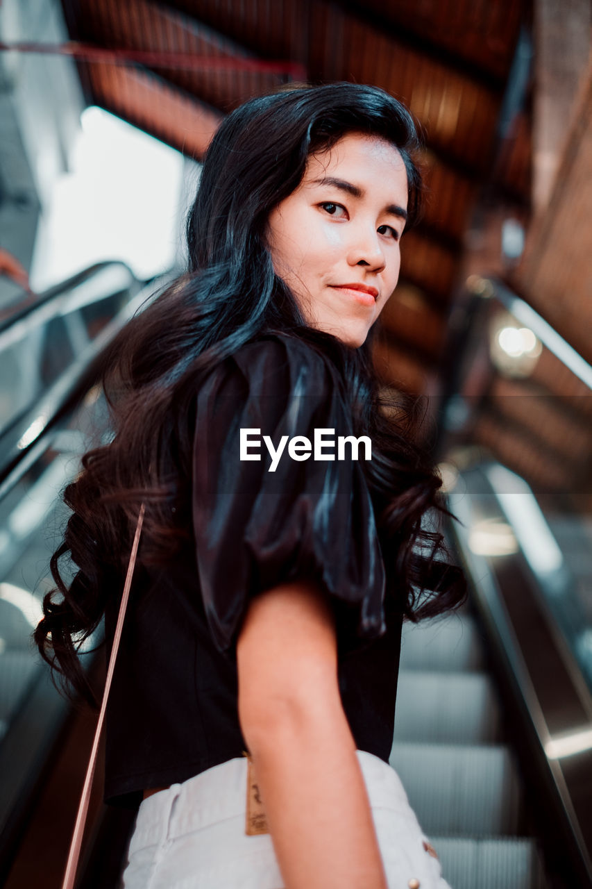 Portrait of young woman standing on escalator