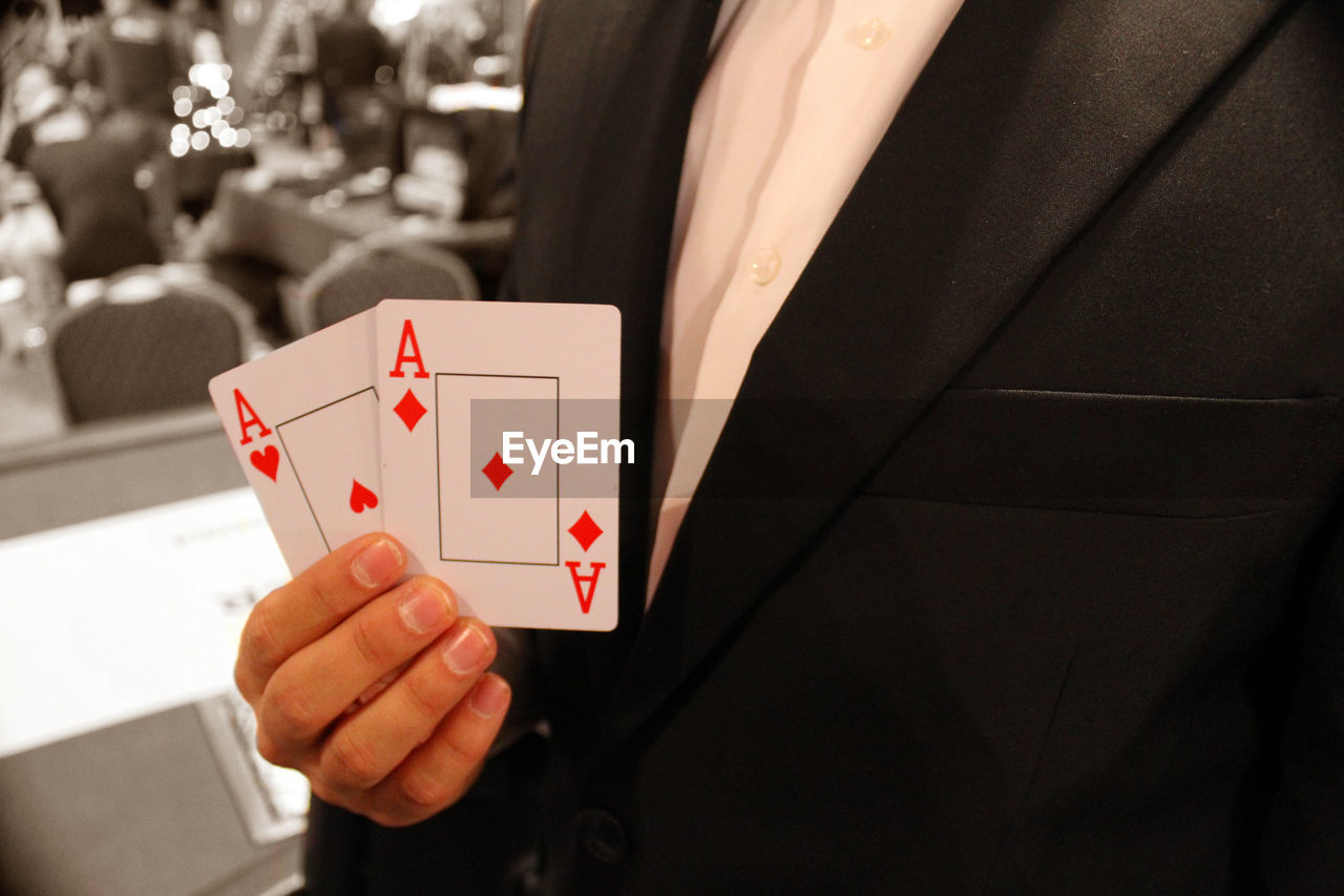 Midsection of businessman holding playing cards