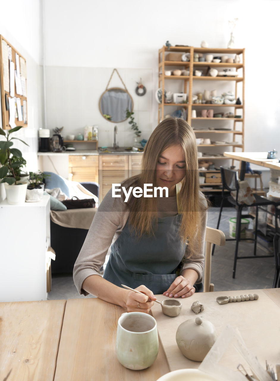 Portrait of a young woman at the ceramic studio. professional potter sculpts a mug out of clay.