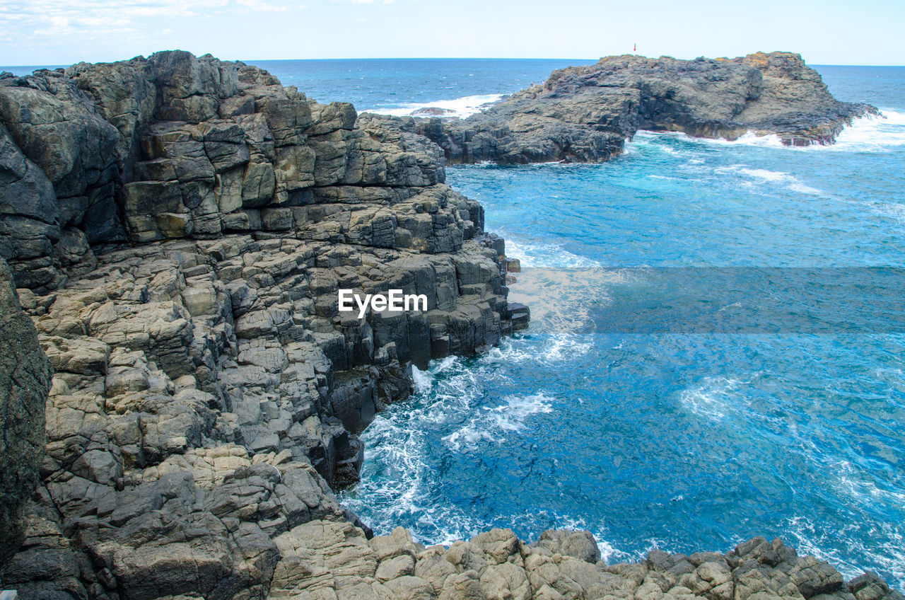 Rock formations by sea against blue sky