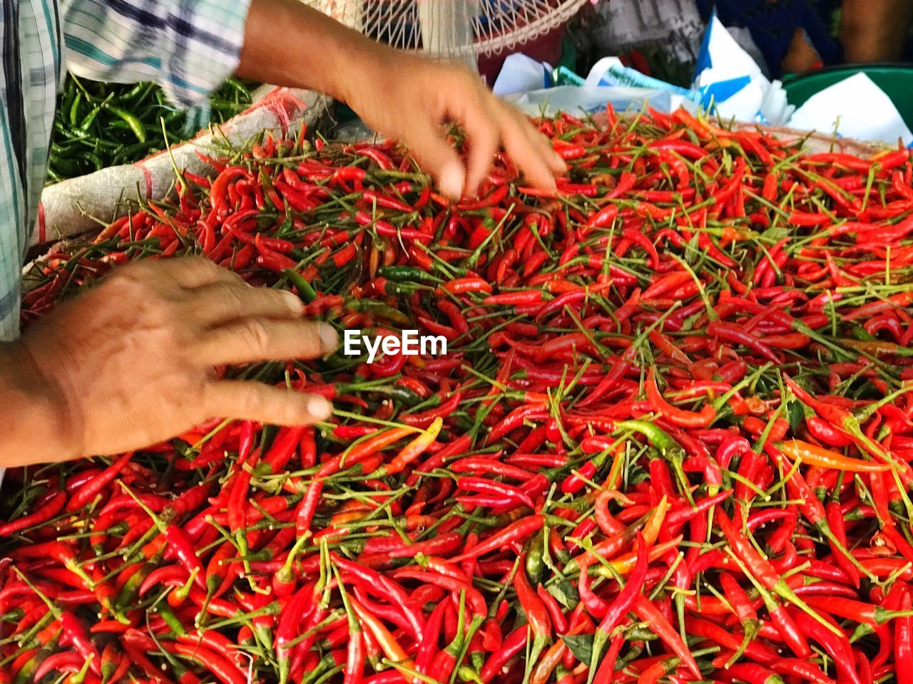 Midsection of person by red chili pepper at market stall