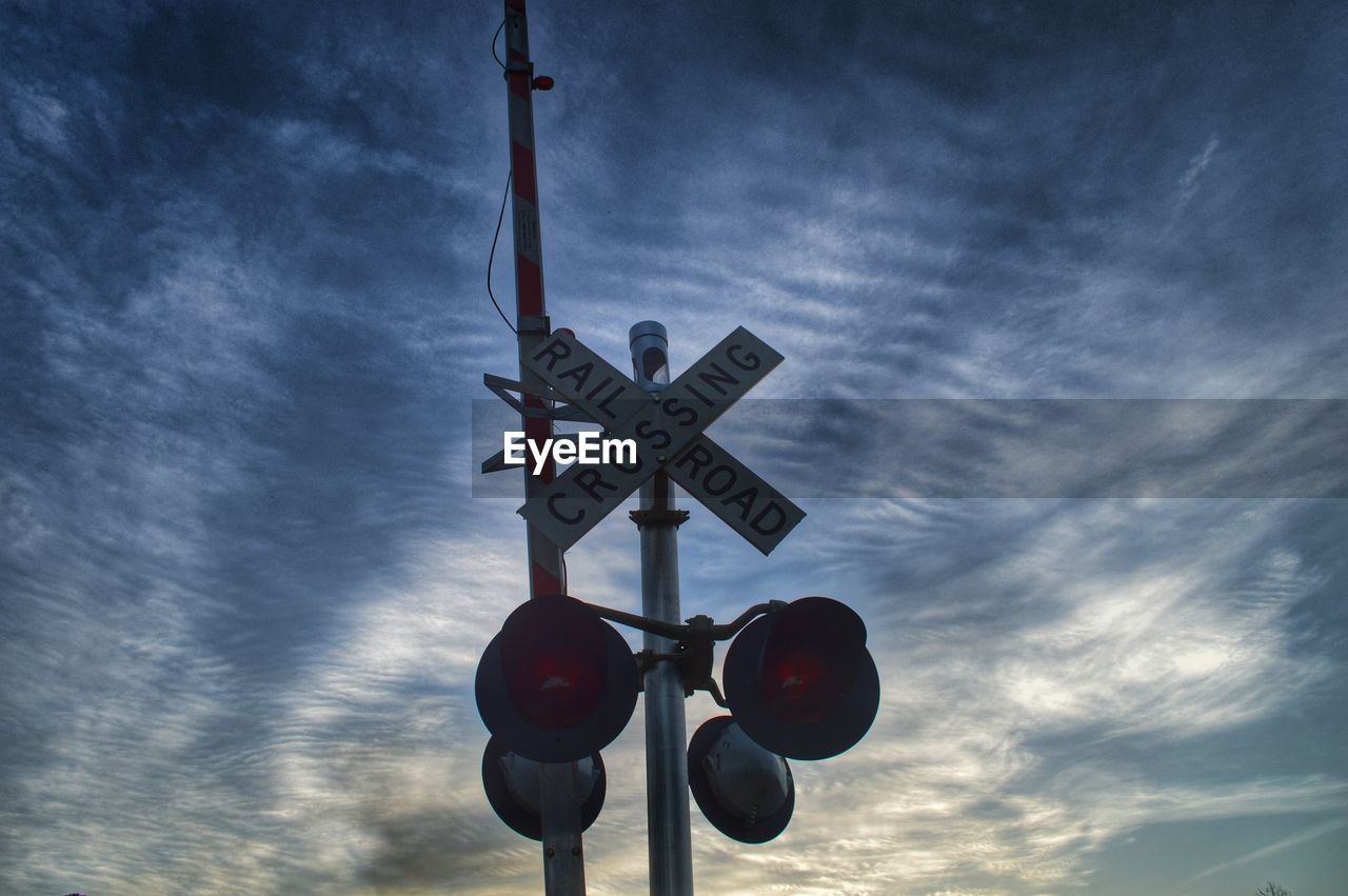 Low angle view of railroad crossing against sky at dusk