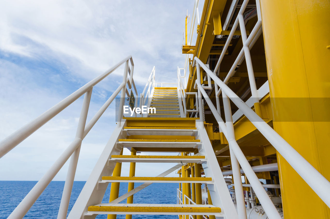 Offshore platform in sea against cloudy sky