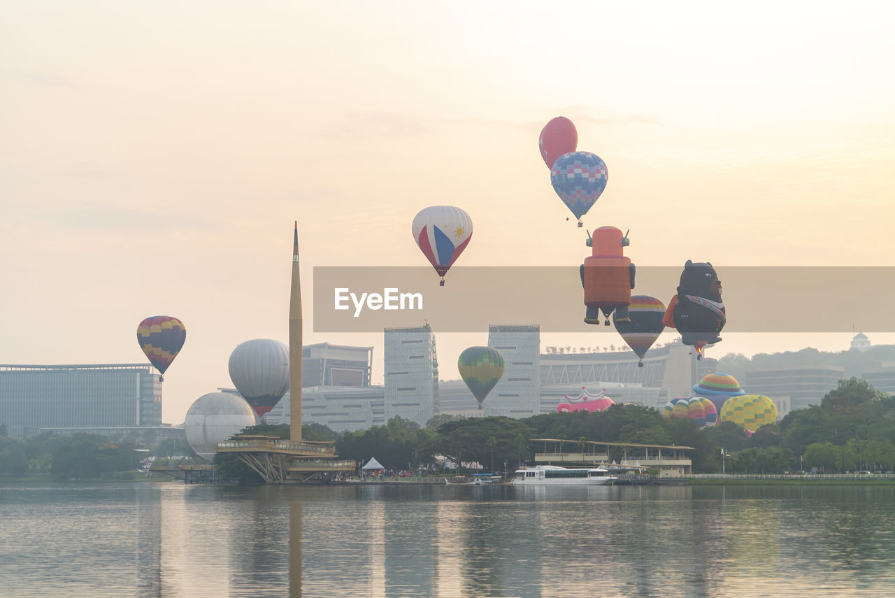 HOT AIR BALLOONS FLYING OVER RIVER AGAINST SKY