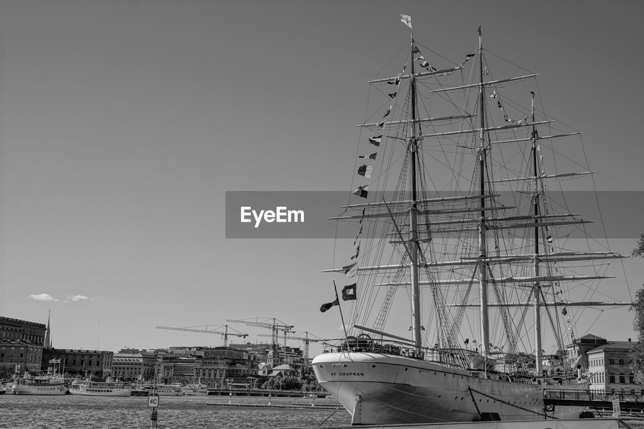 SAILBOATS MOORED IN SEA AGAINST SKY