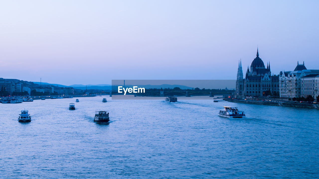 BOATS SAILING IN RIVER AGAINST SKY