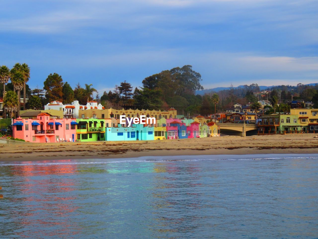 MULTI COLORED HOUSES BY SEA AGAINST SKY