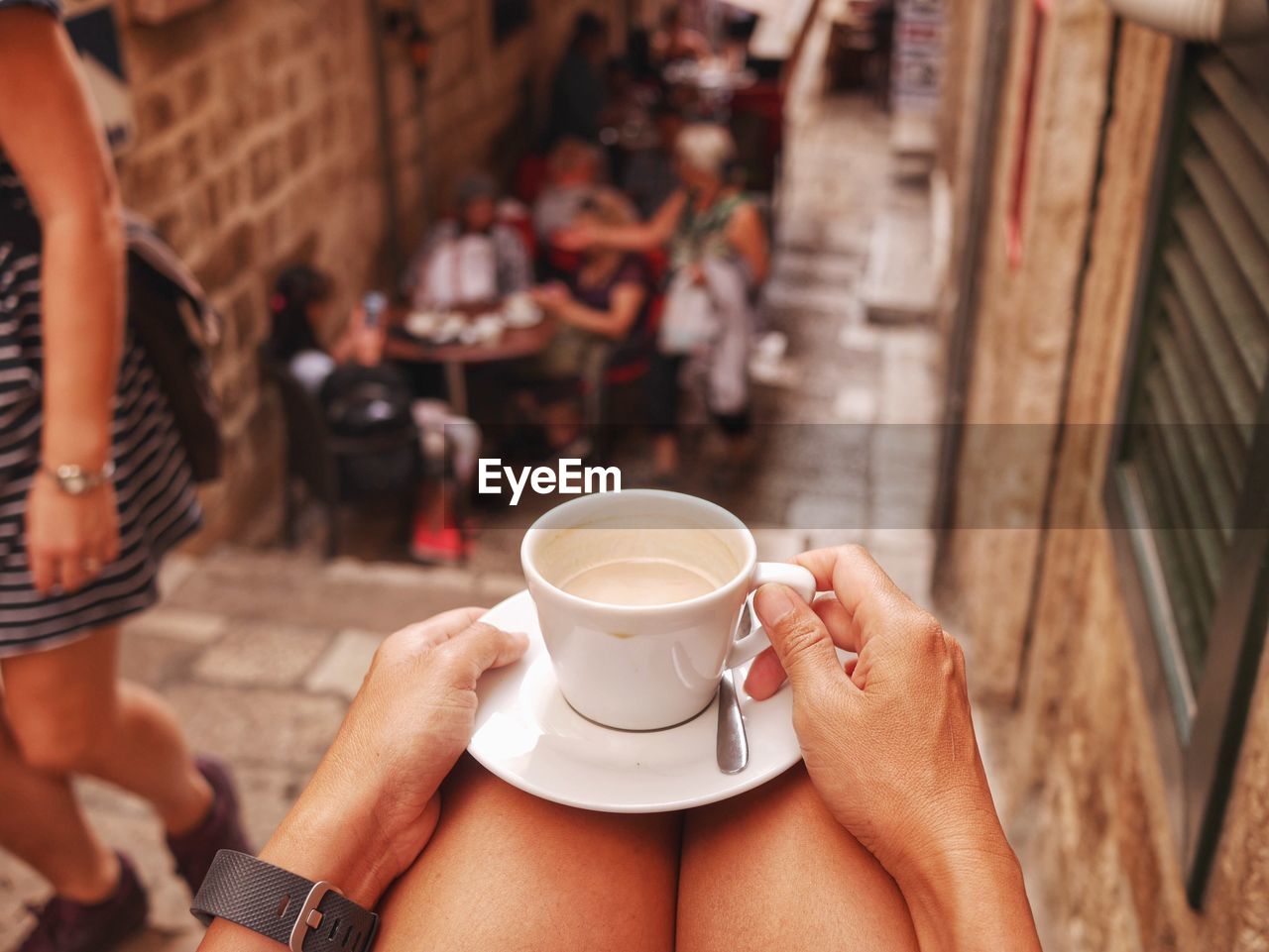 Cropped image of woman having coffee while sitting on steps