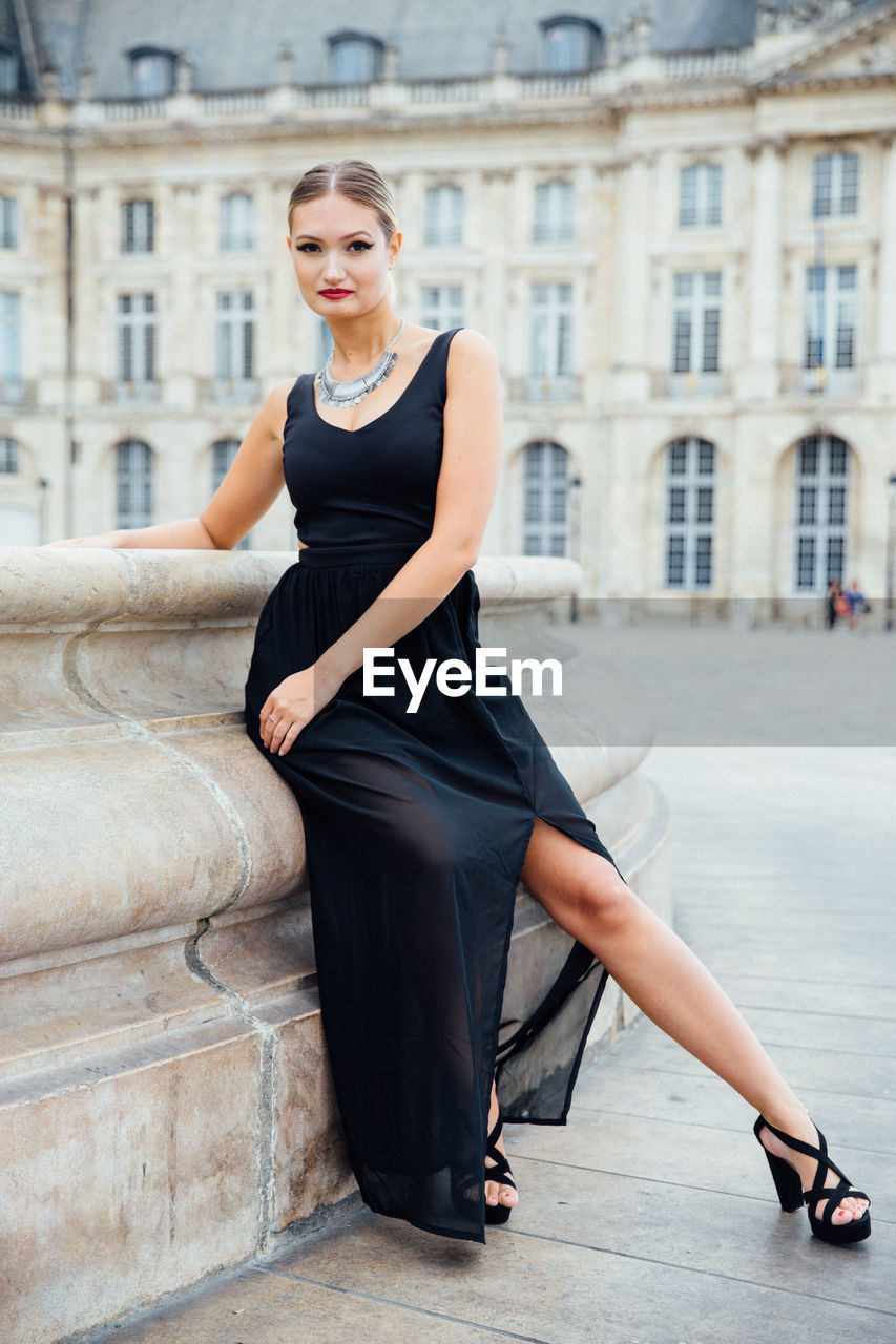 Portrait of confident young woman sitting in city