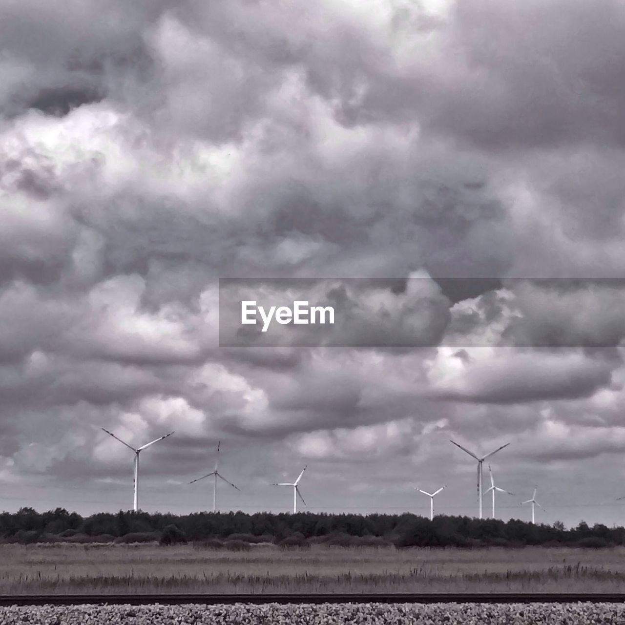 Windmill on field against cloudy sky