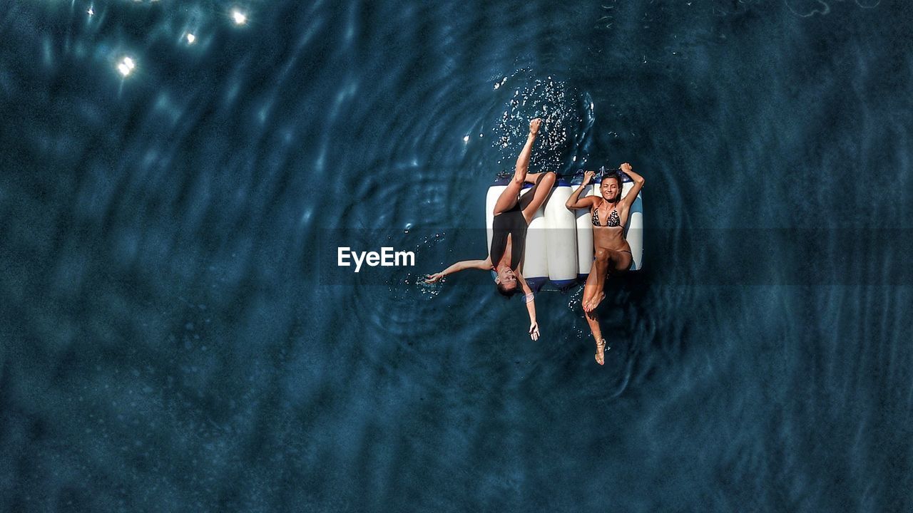 Drone view of friends floating on sea