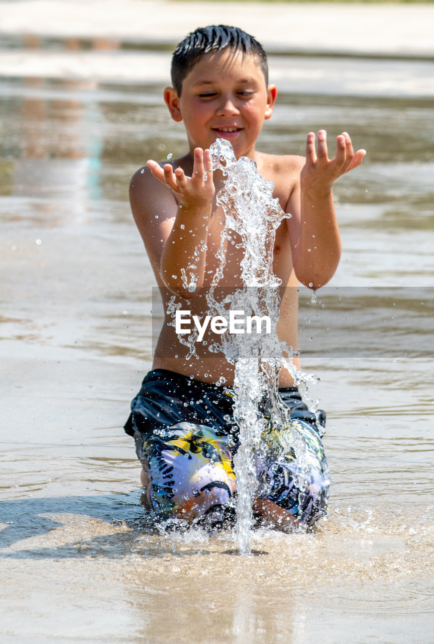 water, childhood, child, swimming, fun, splashing, happiness, one person, motion, men, wet, enjoyment, emotion, nature, smiling, summer, vacation, toddler, cheerful, leisure activity, day, lifestyles, swimwear, outdoors, holiday, front view, trip, positive emotion, person, food and drink, portrait, innocence, joy, three quarter length, beach, cute, clothing, refreshment, bathing, focus on foreground, sunlight