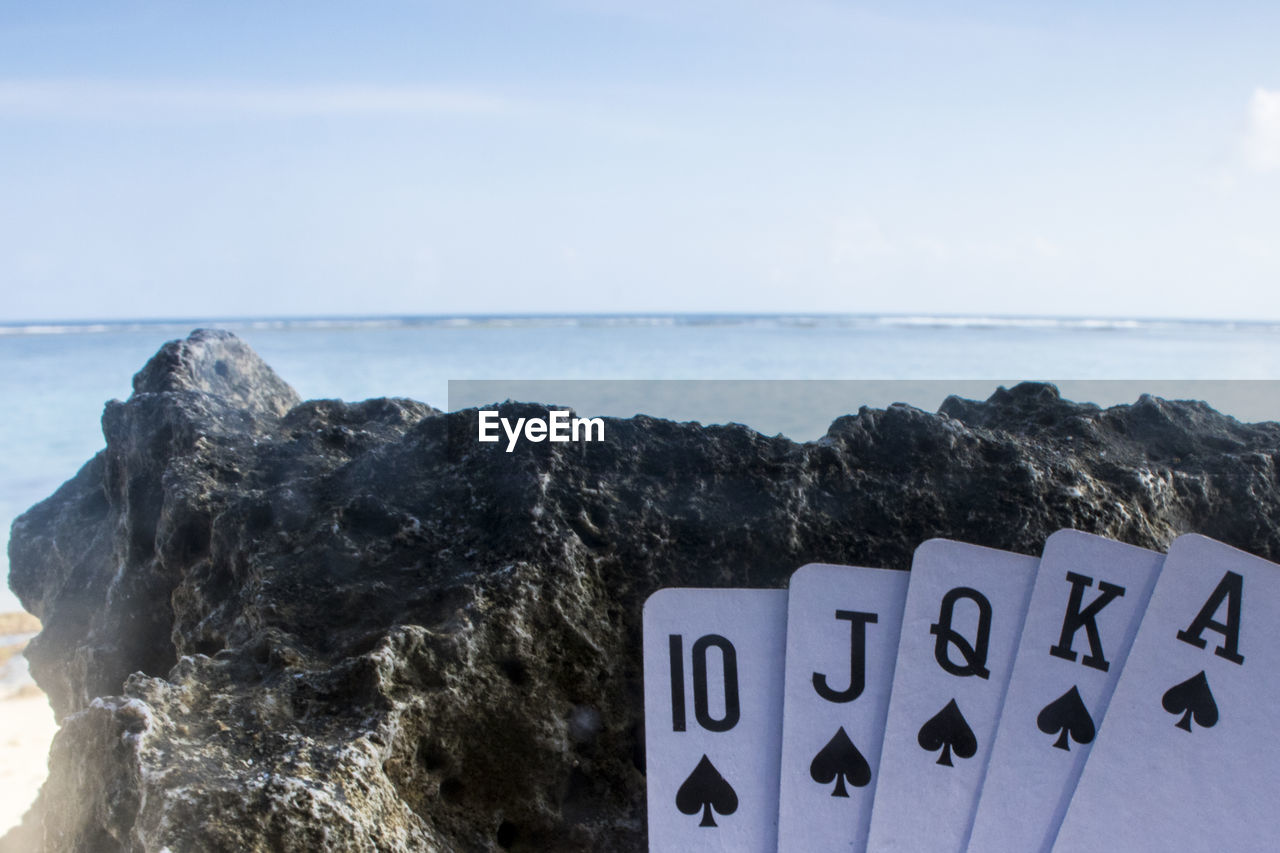 INFORMATION SIGN ON ROCK AT SHORE AGAINST SKY