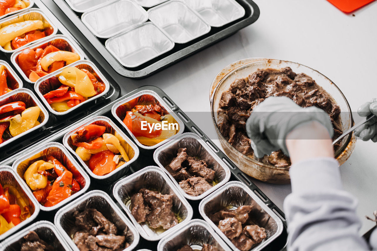 Caterer in a professional kitchen preparing individual servings of roasted vegetables