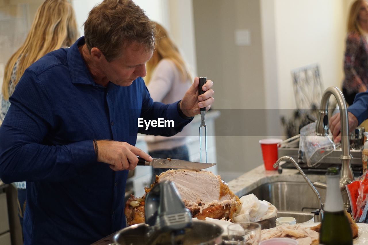 REAR VIEW OF MAN PREPARING FOOD