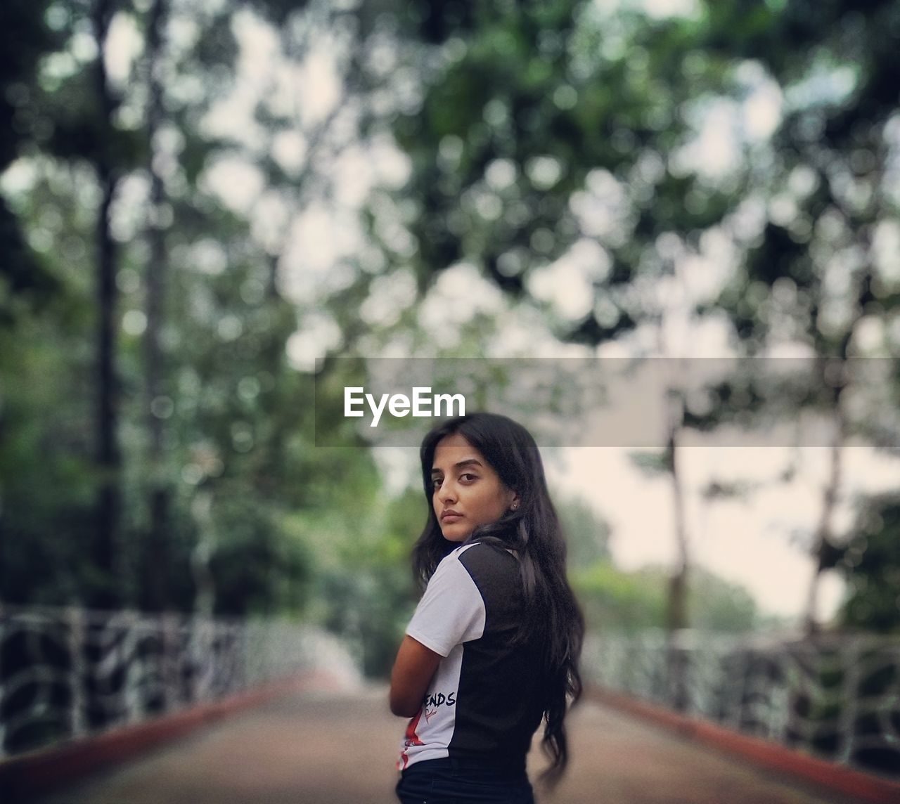 Portrait of young woman standing on footpath