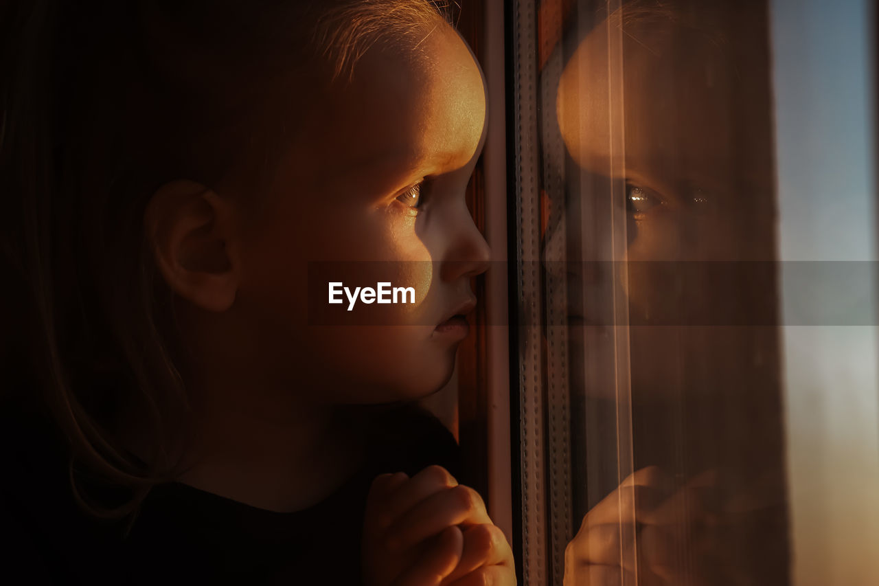 Close-up portrait of boy looking through window
