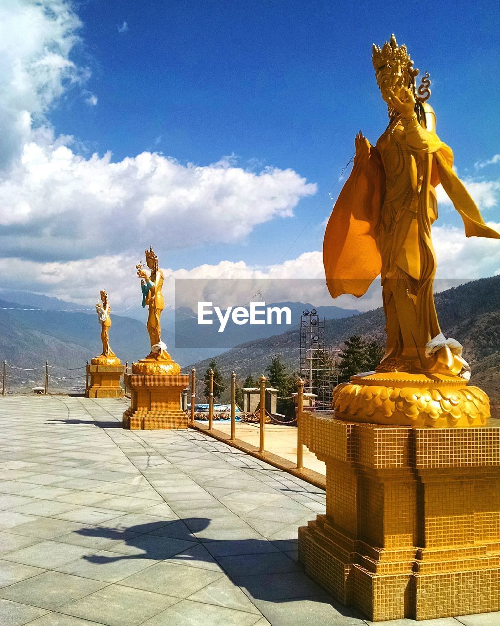 Golden statue against sky and mountains