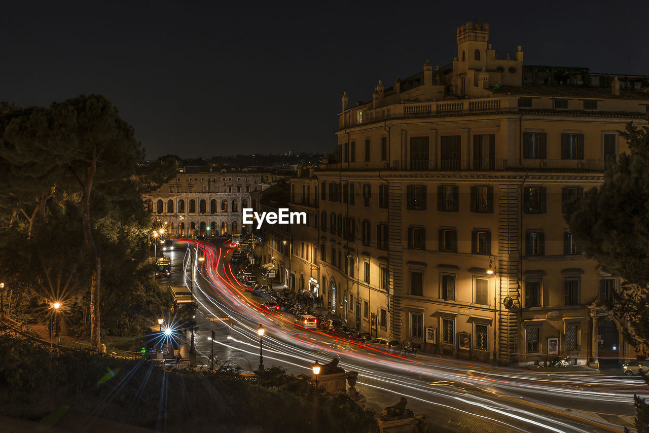 High angle view of light trails on city street against buildings