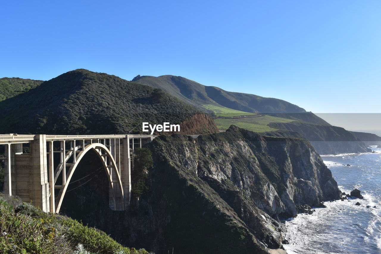 Bridge over mountain against blue sky
