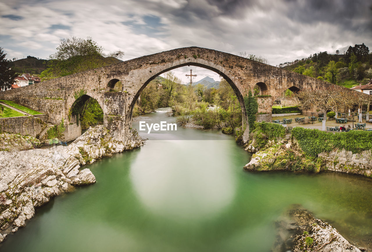 ARCH BRIDGE BY RIVER AGAINST SKY