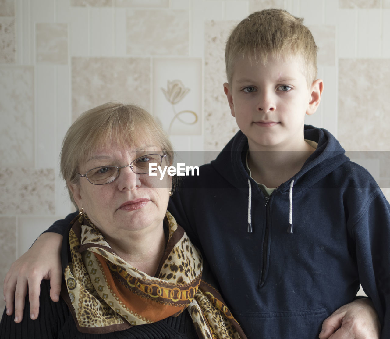 Portrait of senior woman with grandson against tiled wall