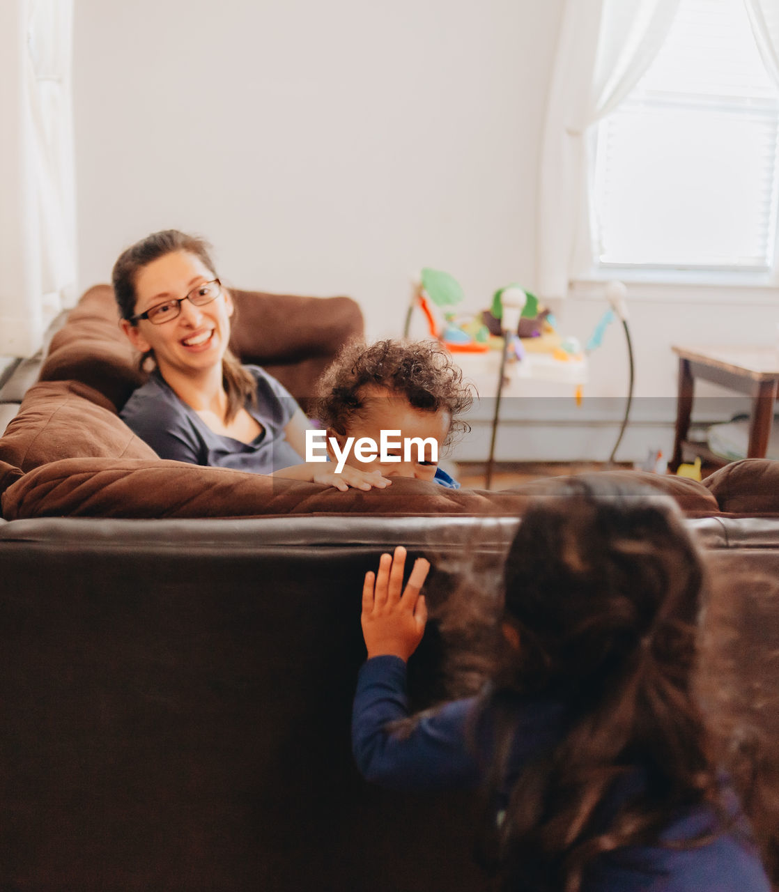 Smiling mother with kids sitting on sofa at home
