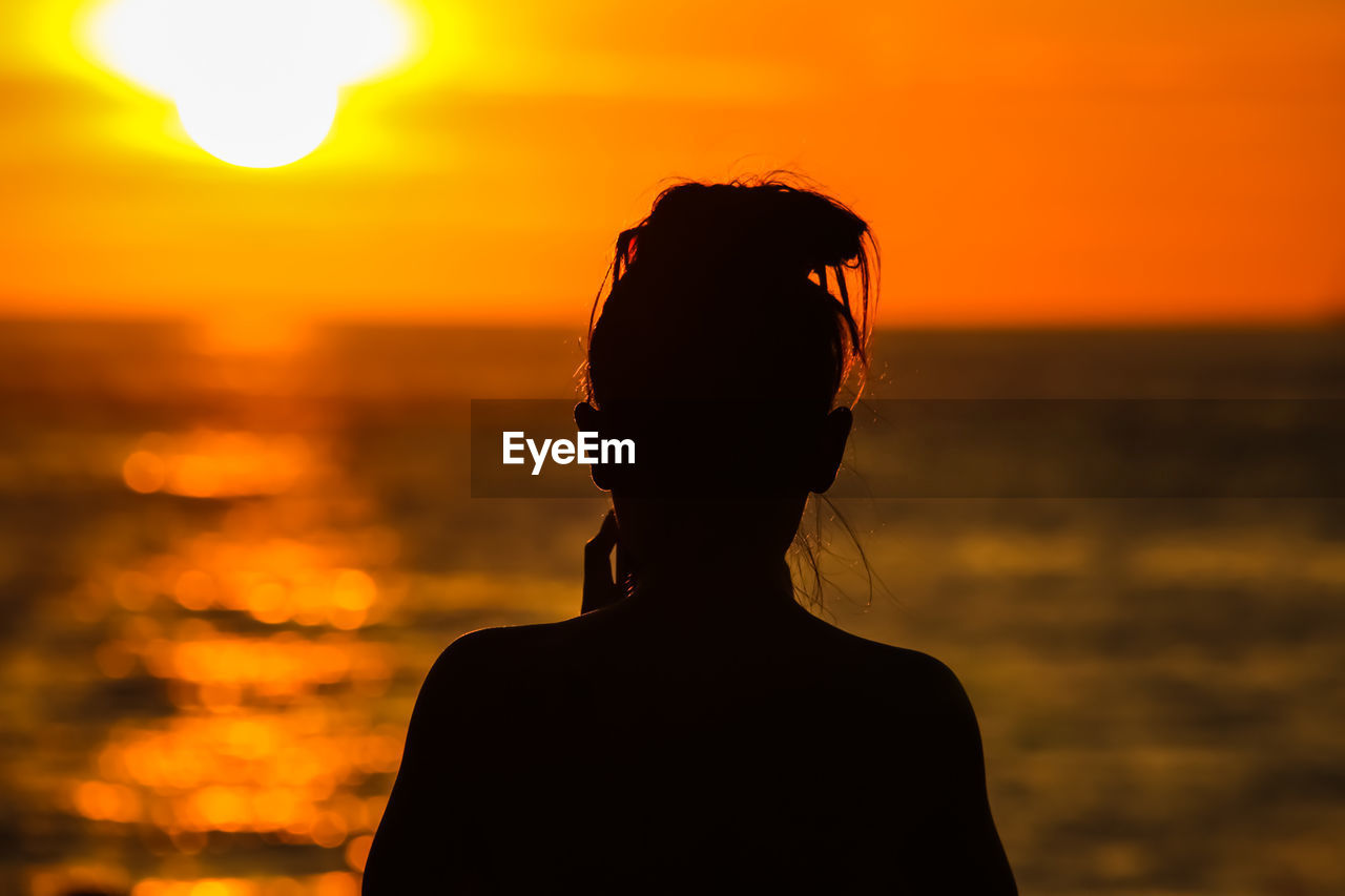 Rear view of silhouette woman against sea during sunset